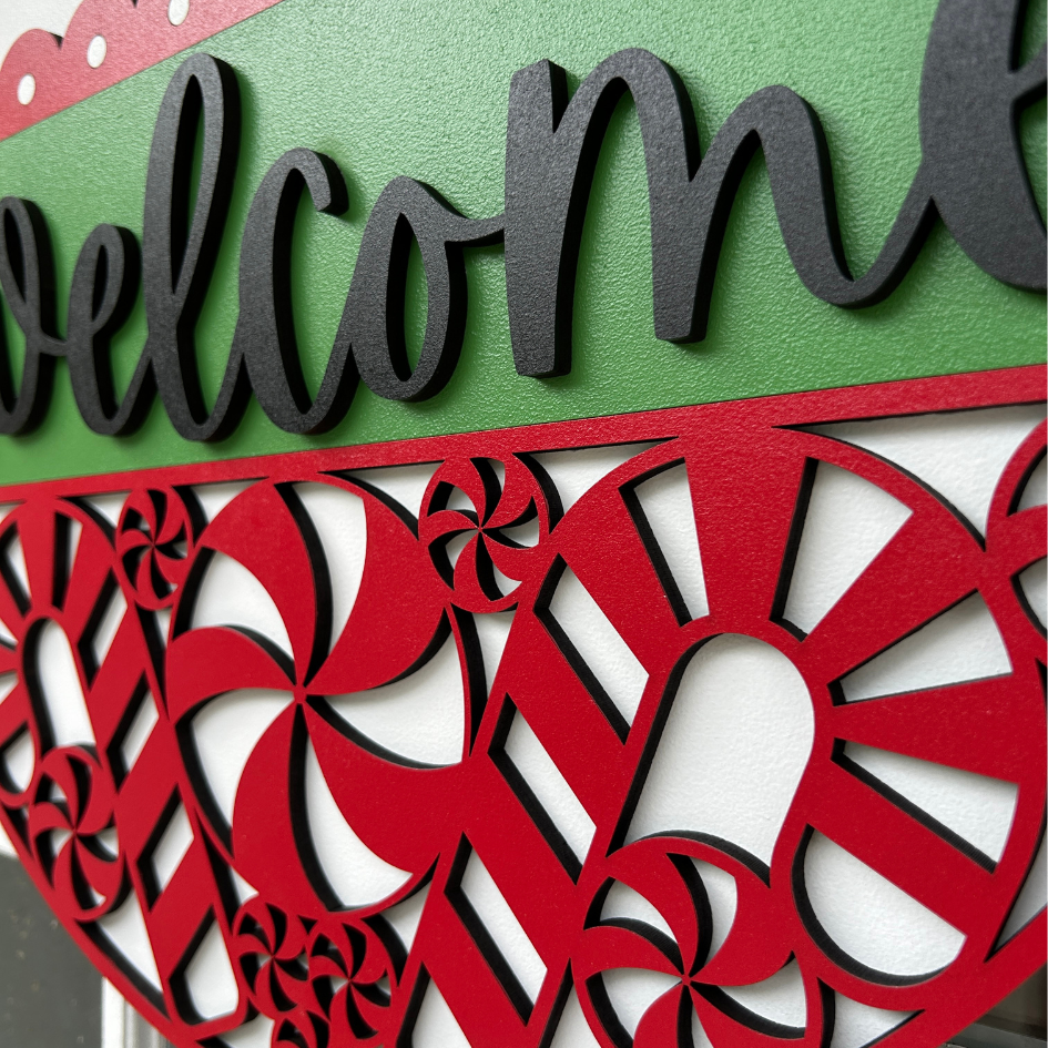Decorative 'welcome' sign with red and green colors and candy cane patterns.