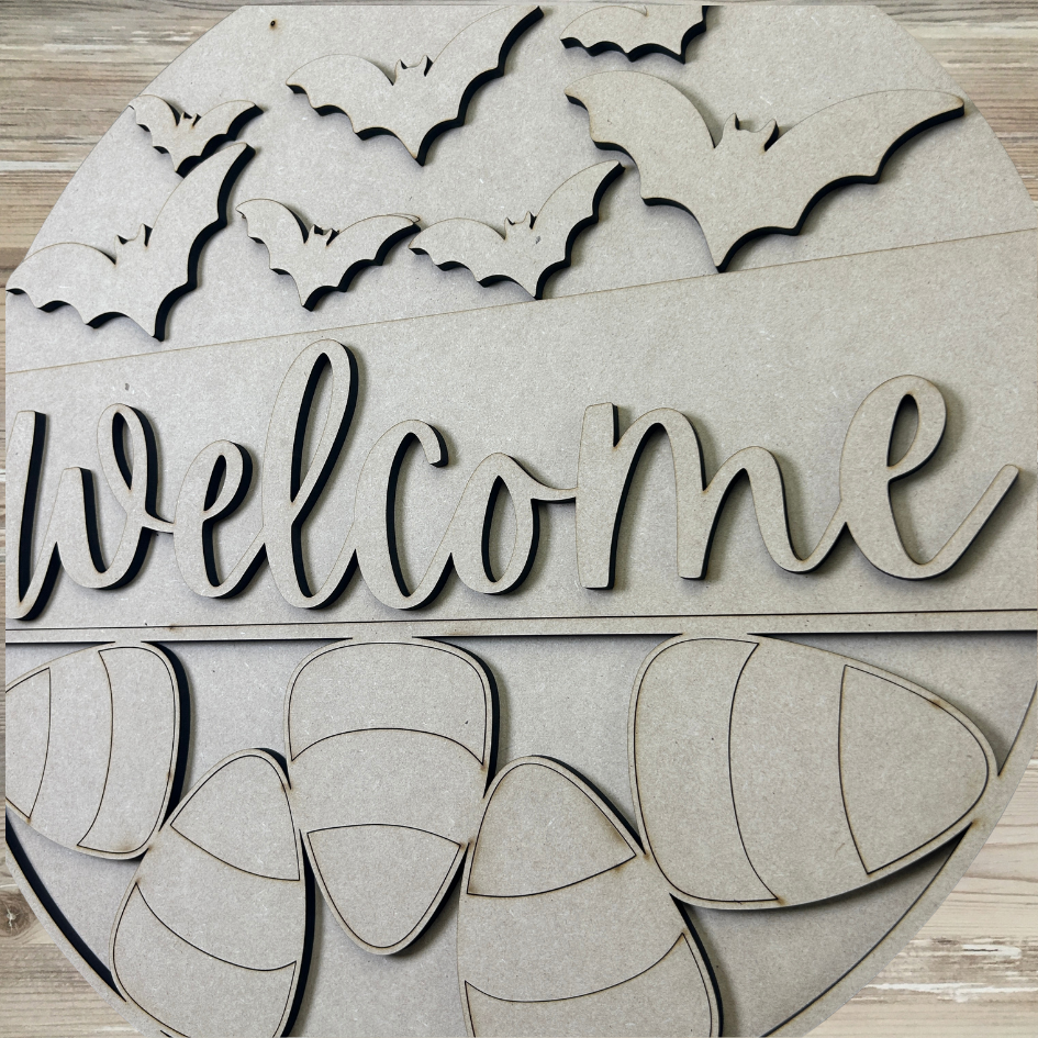 Halloween-themed wooden sign with 'welcome' text, bats, and pumpkins on a wooden background.