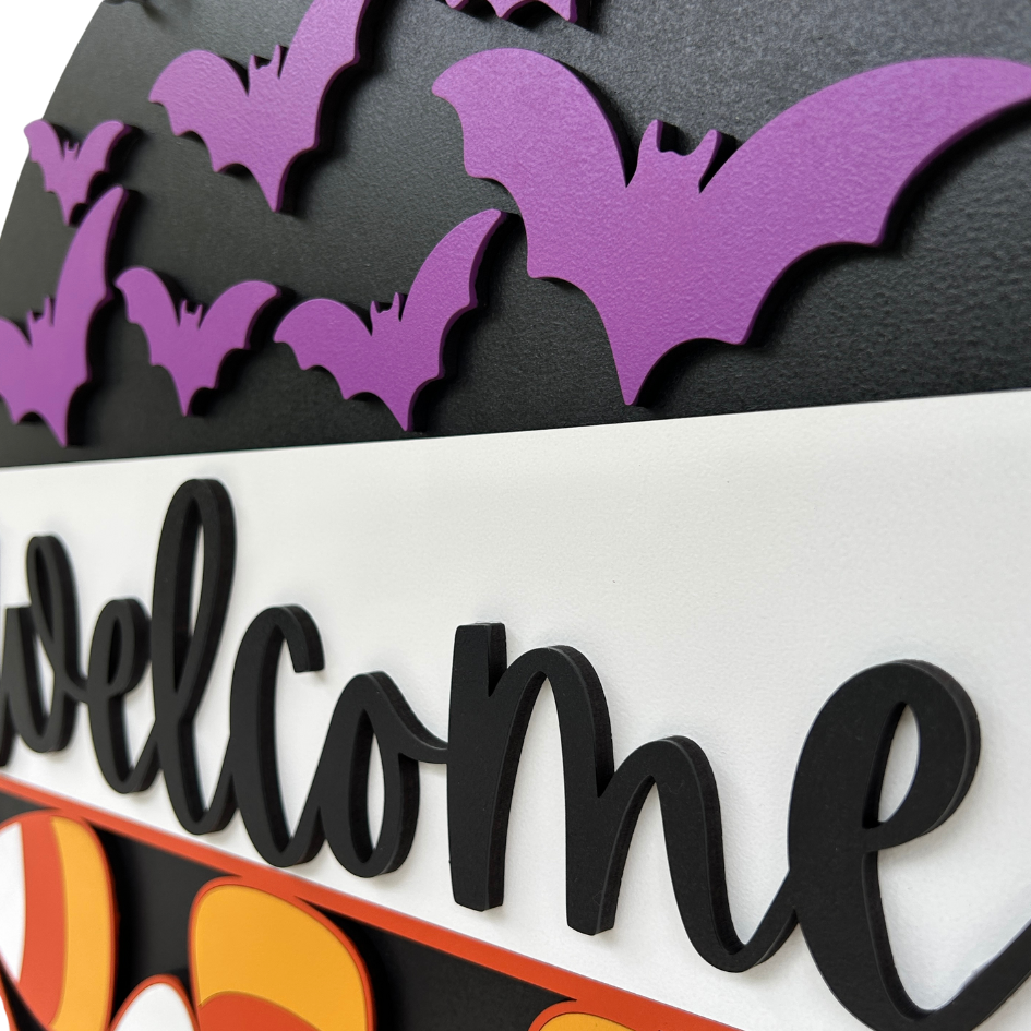 Halloween-themed decorative sign with purple bats and colorful text on a black background