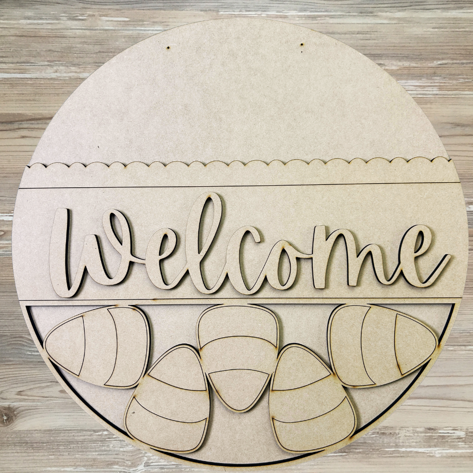 Round wooden sign with 'Welcome' and candy corn design on a wooden background