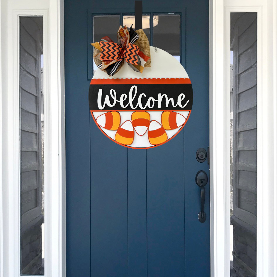 Blue door with Halloween-themed 'Welcome' sign and decorative bow.