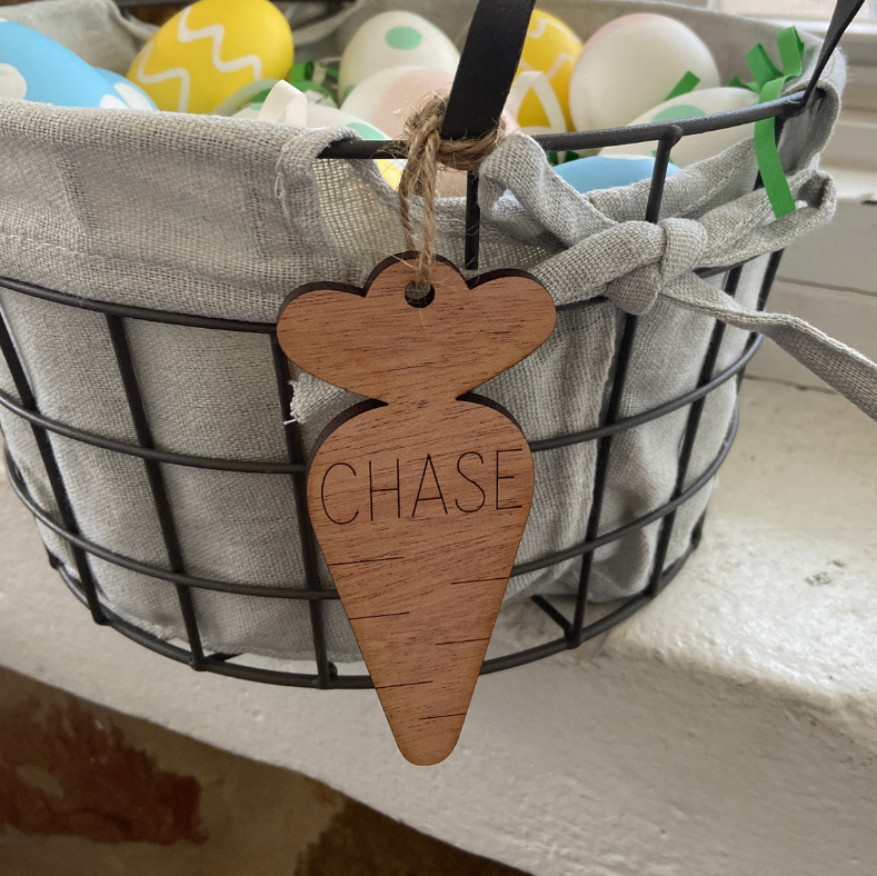 Wooden carrot-shaped tag with 'CHASE' on a wire basket with Easter eggs.