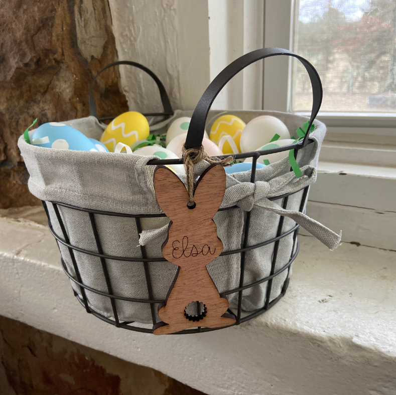 Decorative Easter basket with a wooden bunny cutout labeled 'Elsa' on a windowsill.