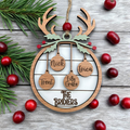 Wooden reindeer ornament with engraved names and 'The Bridiers' on a wooden surface with cranberries and pine branches.