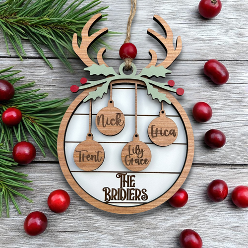 Wooden reindeer ornament with engraved names and 'The Bridiers' on a wooden surface with cranberries and pine branches.