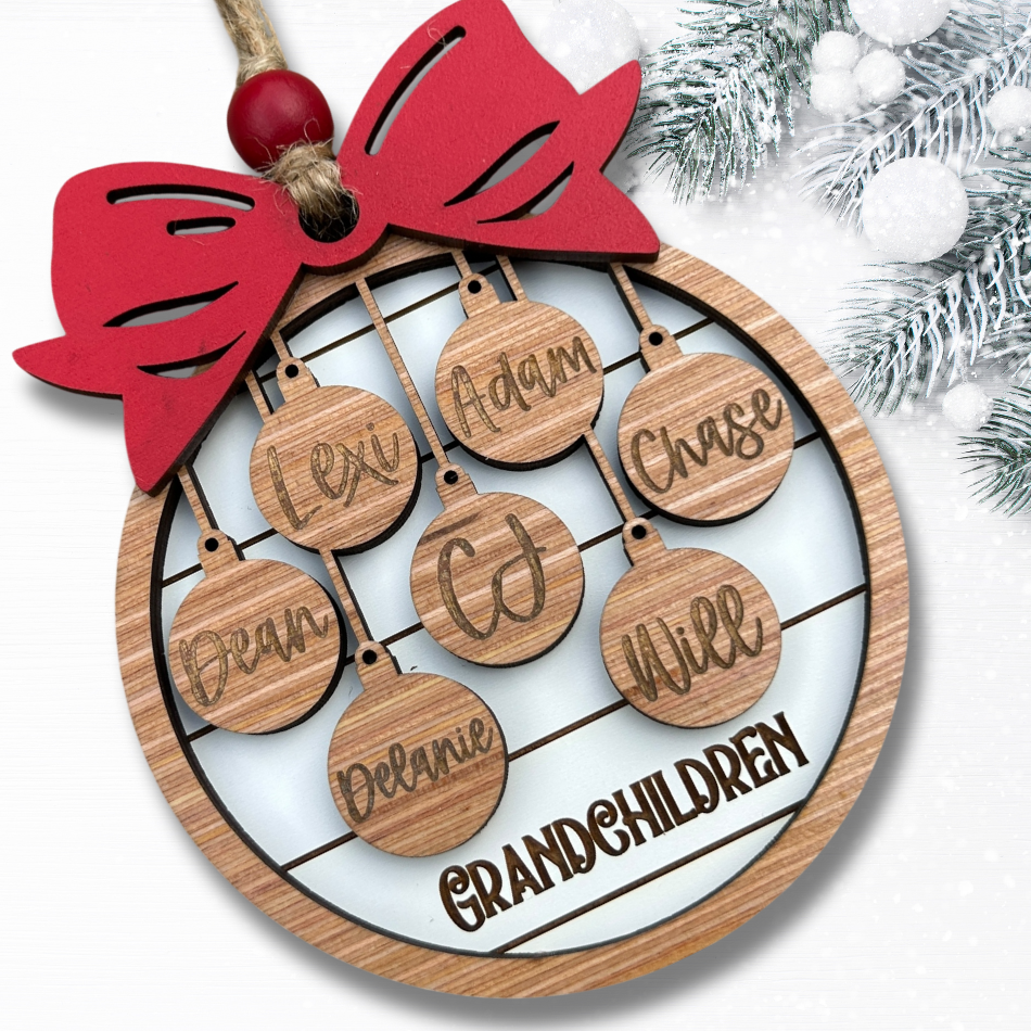 Wooden ornament with names of grandchildren and a red bow, Christmas tree in the background