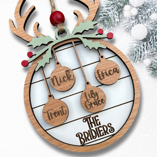Wooden Christmas ornament with names hanging from a reindeer antler design.