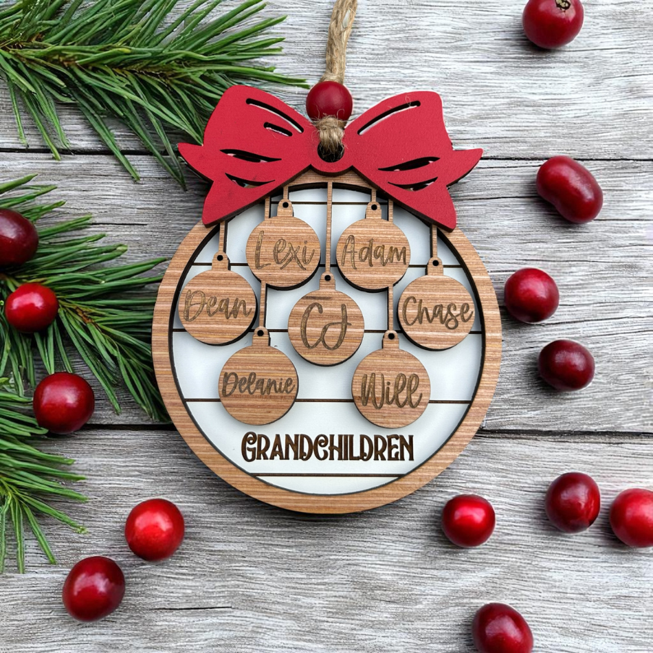 Wooden ornament with names of grandchildren and a red bow, surrounded by cranberries and pine branches on a wooden surface.