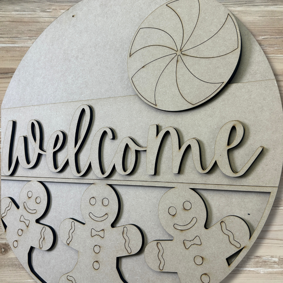 Wooden decorative sign with 'Welcome' text, gingerbread men, and a candy cane on a wooden background.