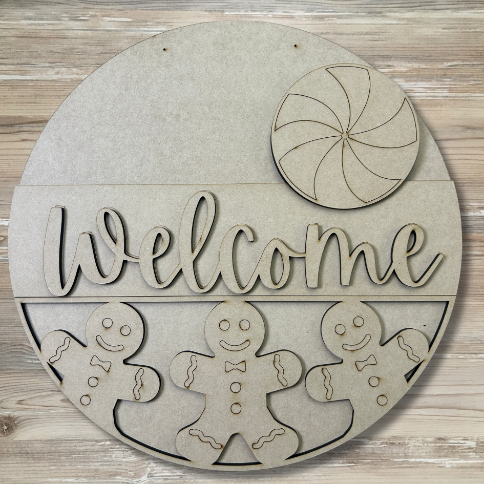 Round wooden sign with 'welcome' text and gingerbread men design on a wooden background
