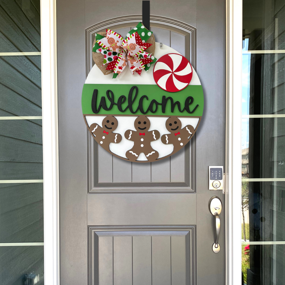 Decorative door hanger with gingerbread men and candy on a gray door