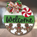 Decorative Christmas door hanger with gingerbread men, candy cane, and bow on a wooden surface.