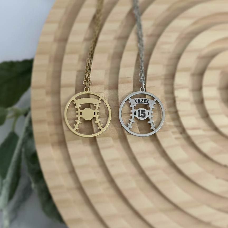 Two stainless steel baseball shaped necklaces with on a wooden surface.