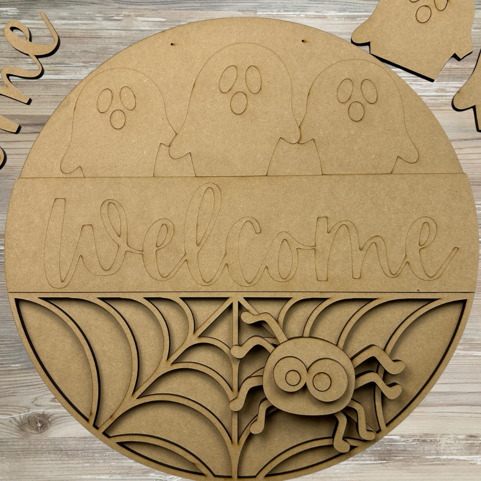 Halloween-themed wooden sign with 'Welcome' text, ghosts, and a spider on a wooden background.