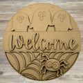 Round wooden cutout with Halloween designs including ghosts, a spider, and 'Welcome' text on a wooden background.