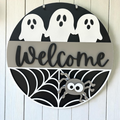Black Halloween welcome sign with ghost and a spider web.