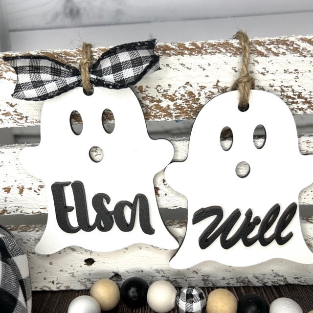 Both boy and girl ghost tags hanging on a shiplap bucket.