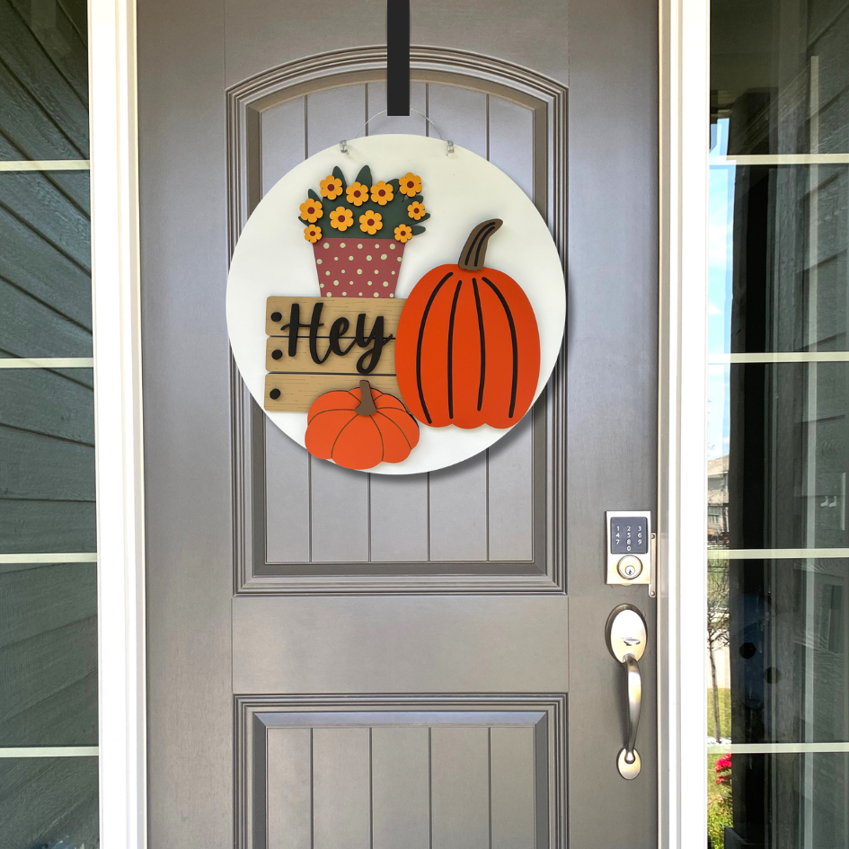 Decorative door hanger with pumpkins and flowers on a gray door