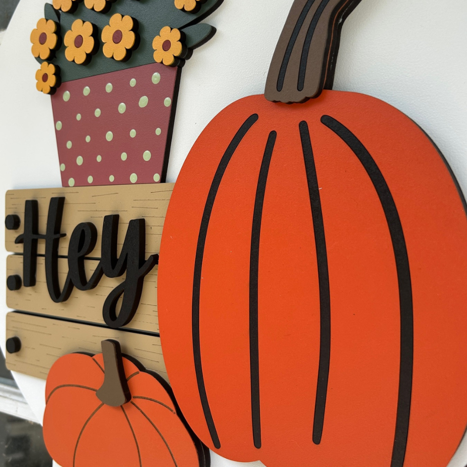 Decorative wall art with pumpkins, flowers, and a 'Hey' sign on a white background