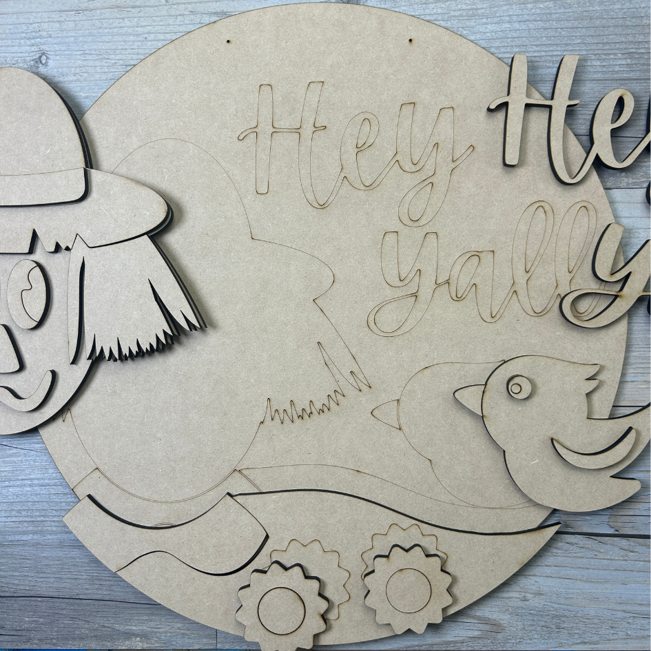 Wooden cutout with 'Hey Y'all' text and decorative elements on a wooden surface