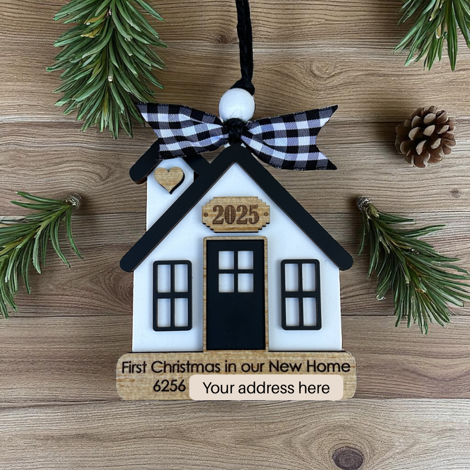 House-shaped ornament with 'First Christmas in our New Home' text on a wooden background
