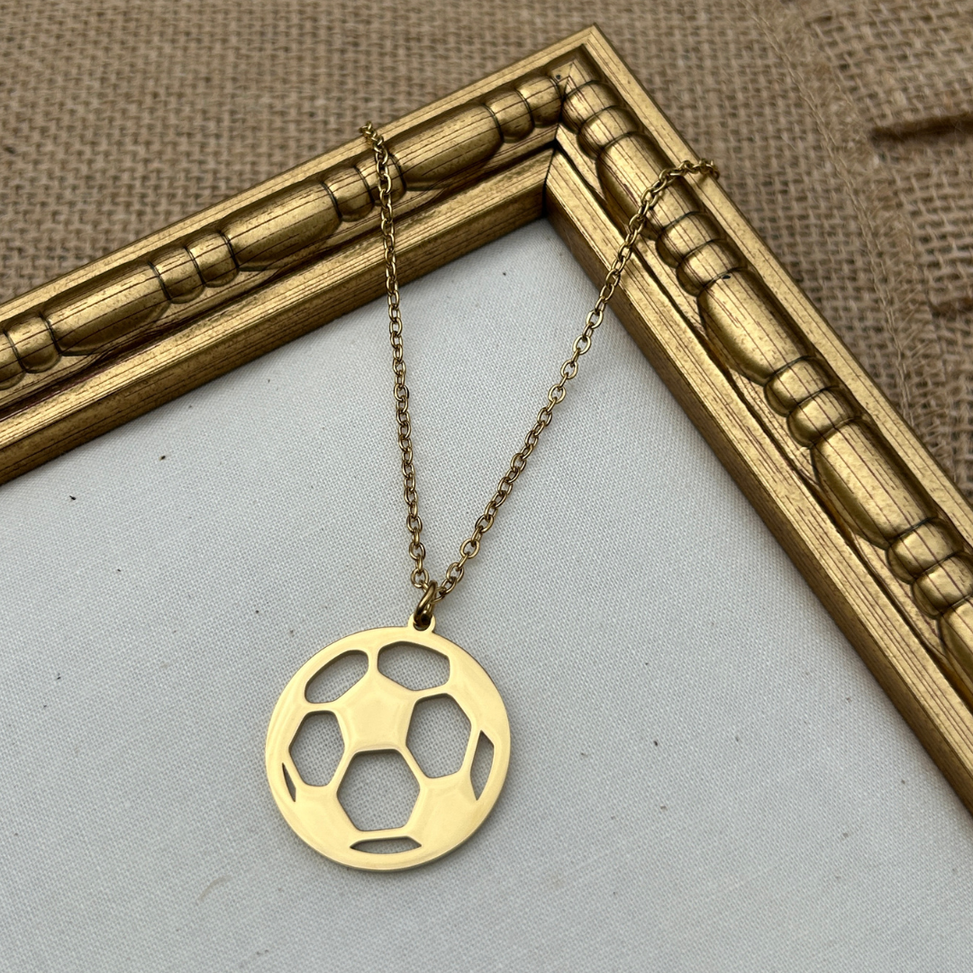 Gold necklace with a soccer ball pendant on a light gray background