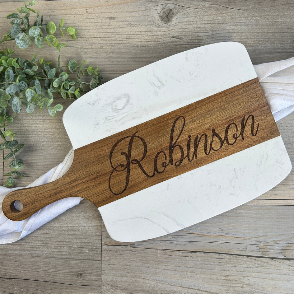 Wooden cutting board with 'Robinson' engraving on a wooden surface with greenery.