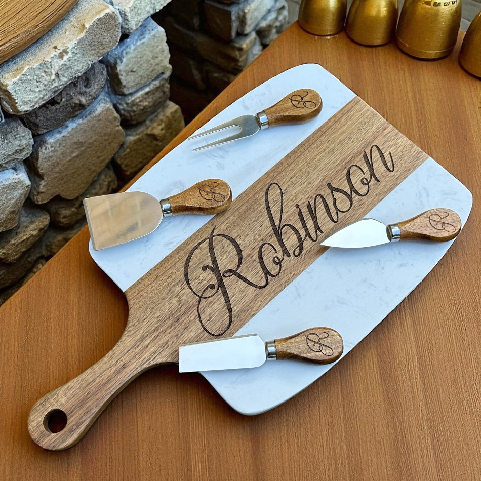 Wooden cheese board set with engraved name 'Robinson' on a marble base, placed on a wooden surface.