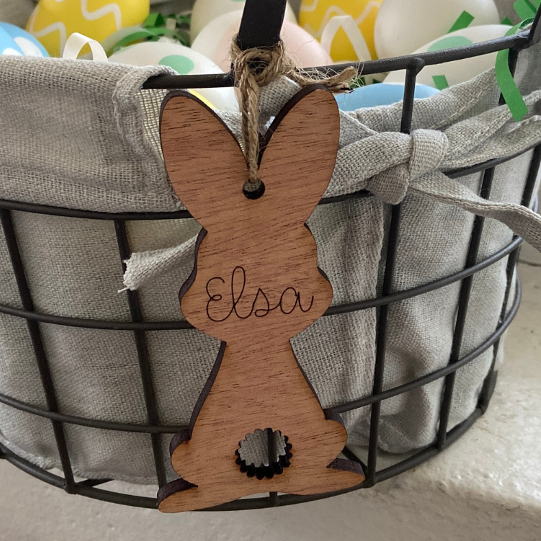 Wooden bunny ornament with 'Elsa' on a wire basket with Easter eggs.