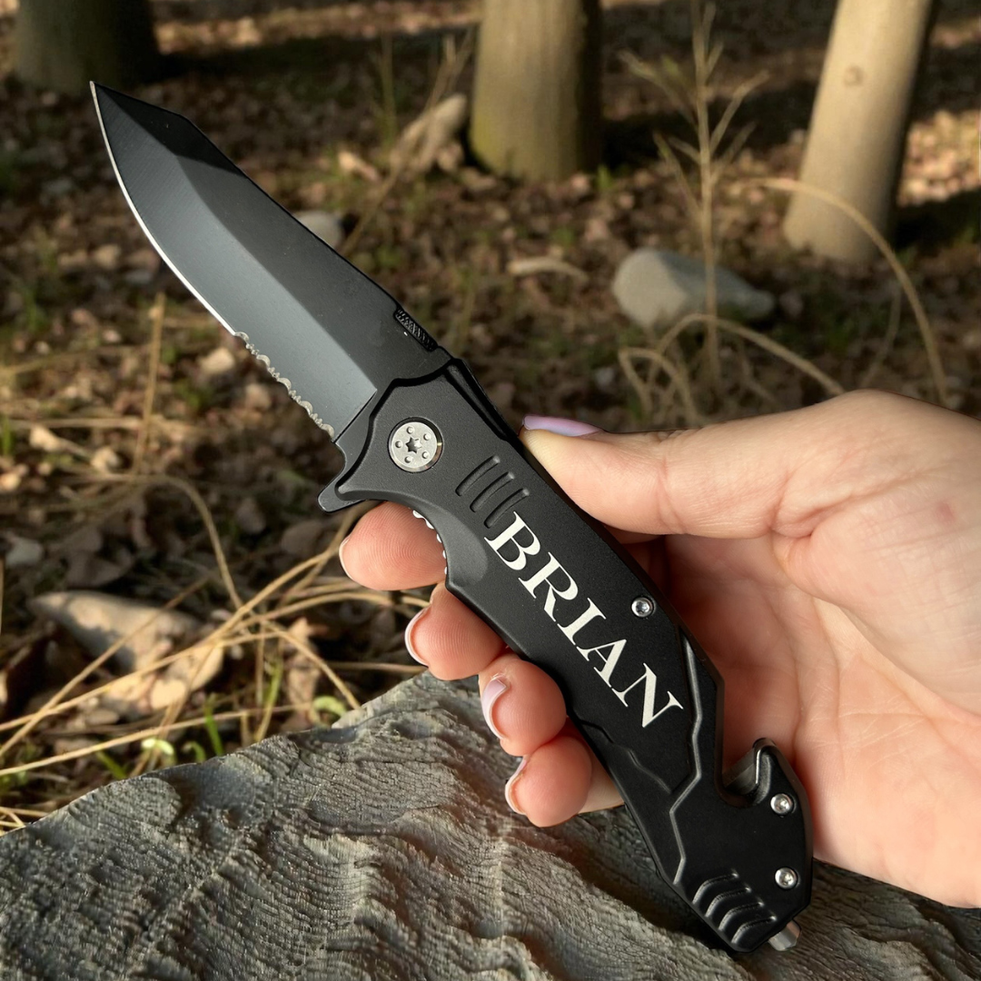 Folding knife with 'BRIAN' engraving held in a hand against a natural background
