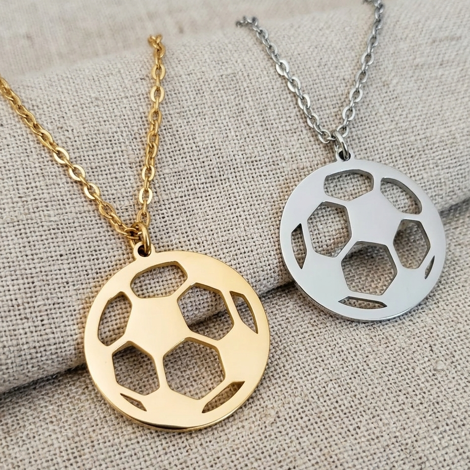 Gold and silver soccer ball pendants on fabric background