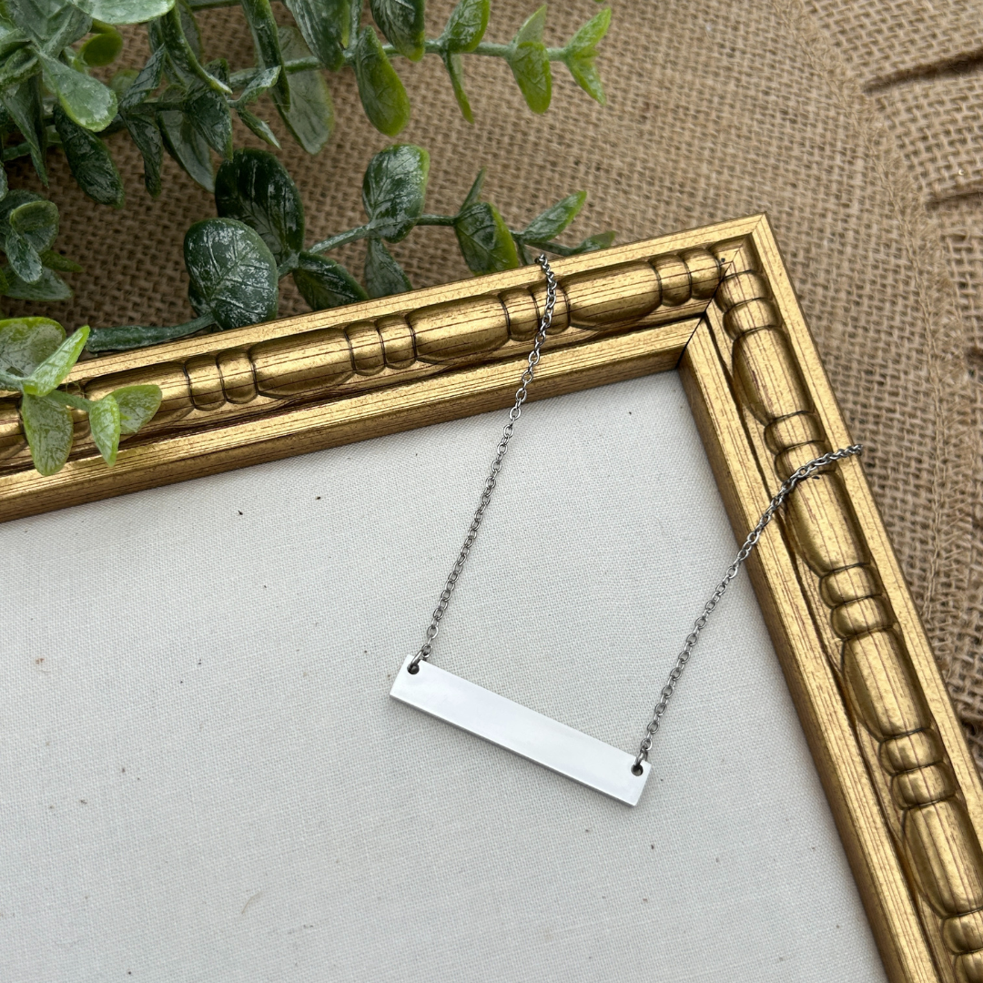 Silver necklace with a rectangular pendant hanging from a gold frame.