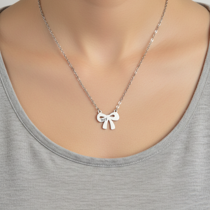 Silver necklace with a bow pendant on a person wearing a gray tank top.