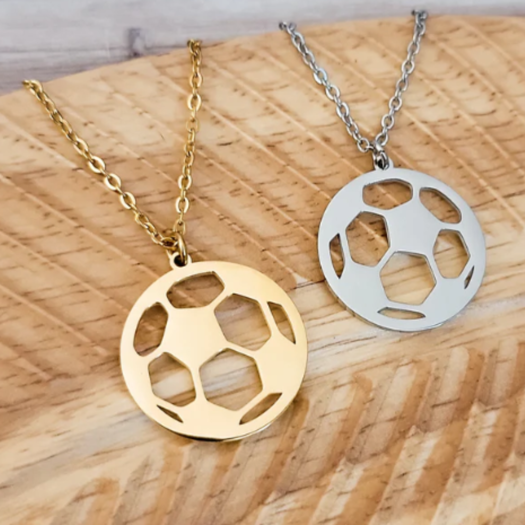 Gold and silver soccer ball pendants on chains on a wooden surface