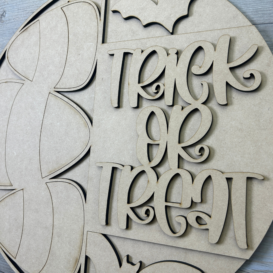 Wooden cutout letters spelling 'Treat or Trick' on a wooden board.