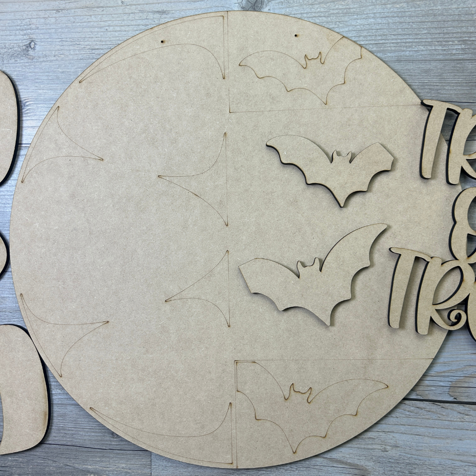 Round cardboard cutout with bat shapes and text on a wooden surface