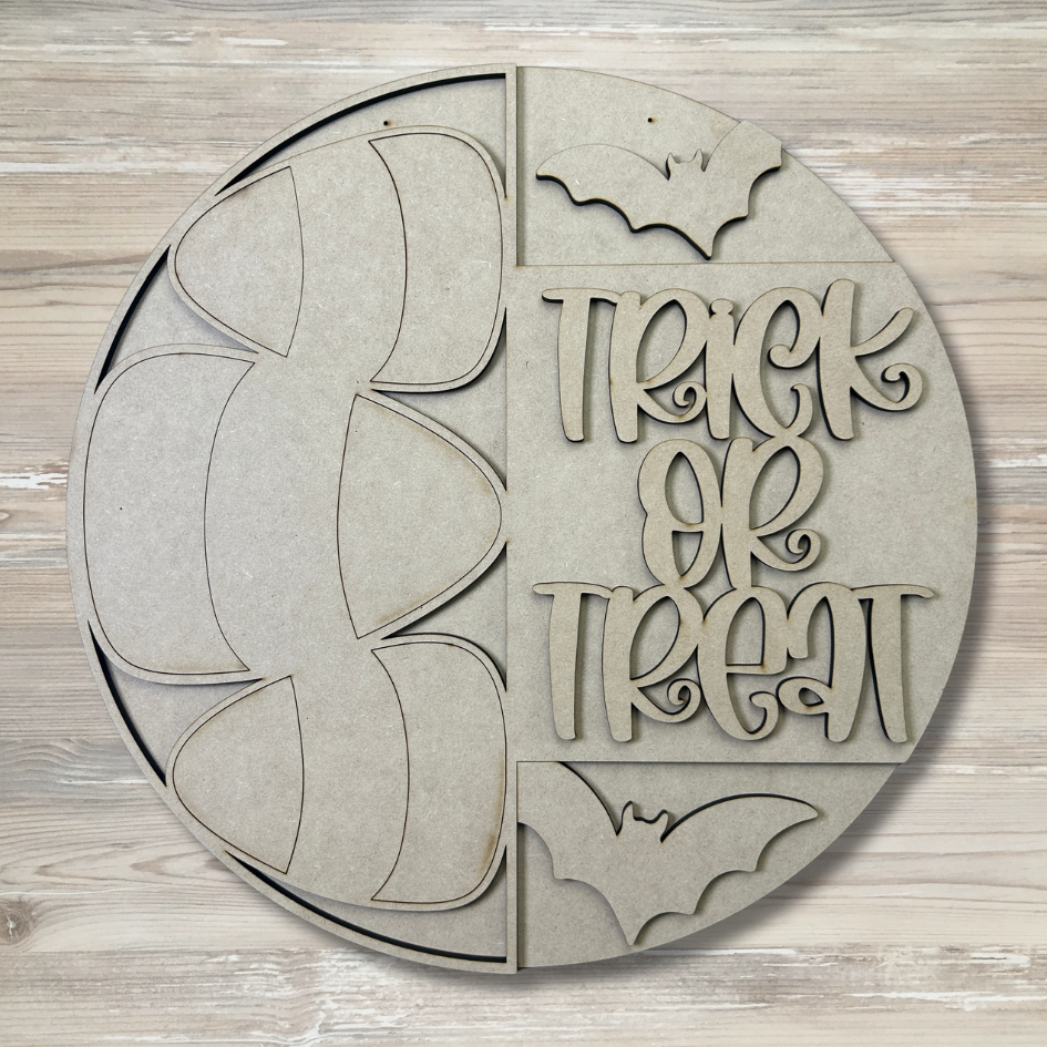 Circular wooden cutout with 'Trick or Treat' text and bat shapes on a wooden background