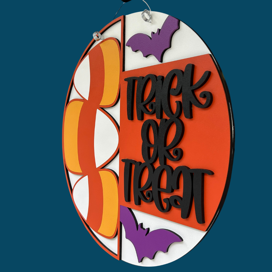 Halloween-themed decorative sign with 'Trick or Treat' text and candy corn design on a blue background.