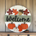 Welcome front door sign with fall leaves, an acorn and pumpkins.