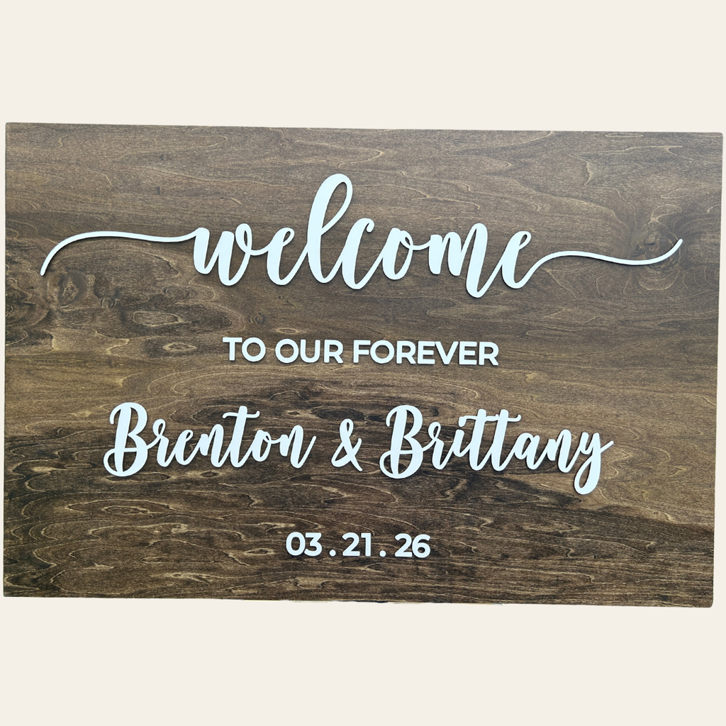 Wooden sign with 'welcome to our forever' text and personalized names and date.