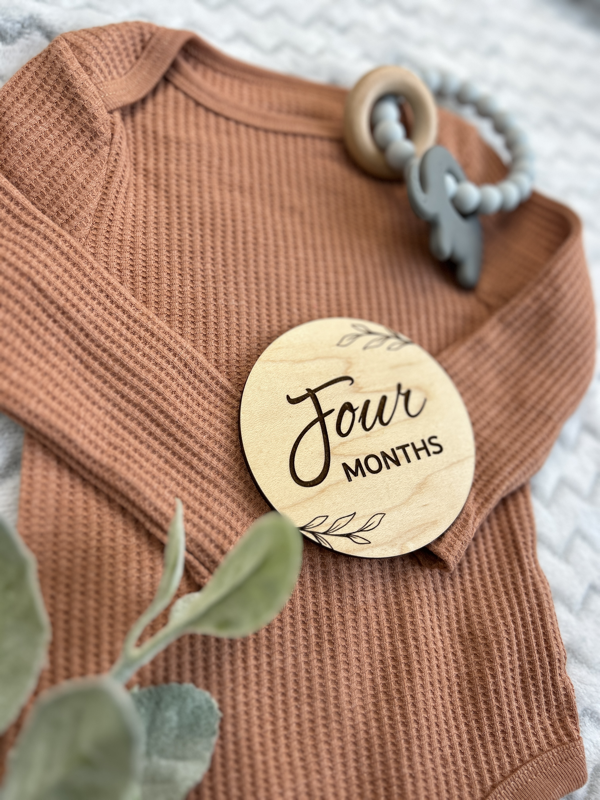 The four months milestone shown on a baby outfit.