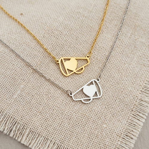 Two gold necklaces with geometric heart designs on a textured fabric background