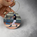 Round photo bag tag with a baseball player and text '#14 WILL' held by a hand on a gray background.