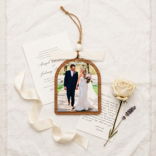 Decorative photo ornament with a couple's wedding photo, ribbon, and rose on a textured surface.