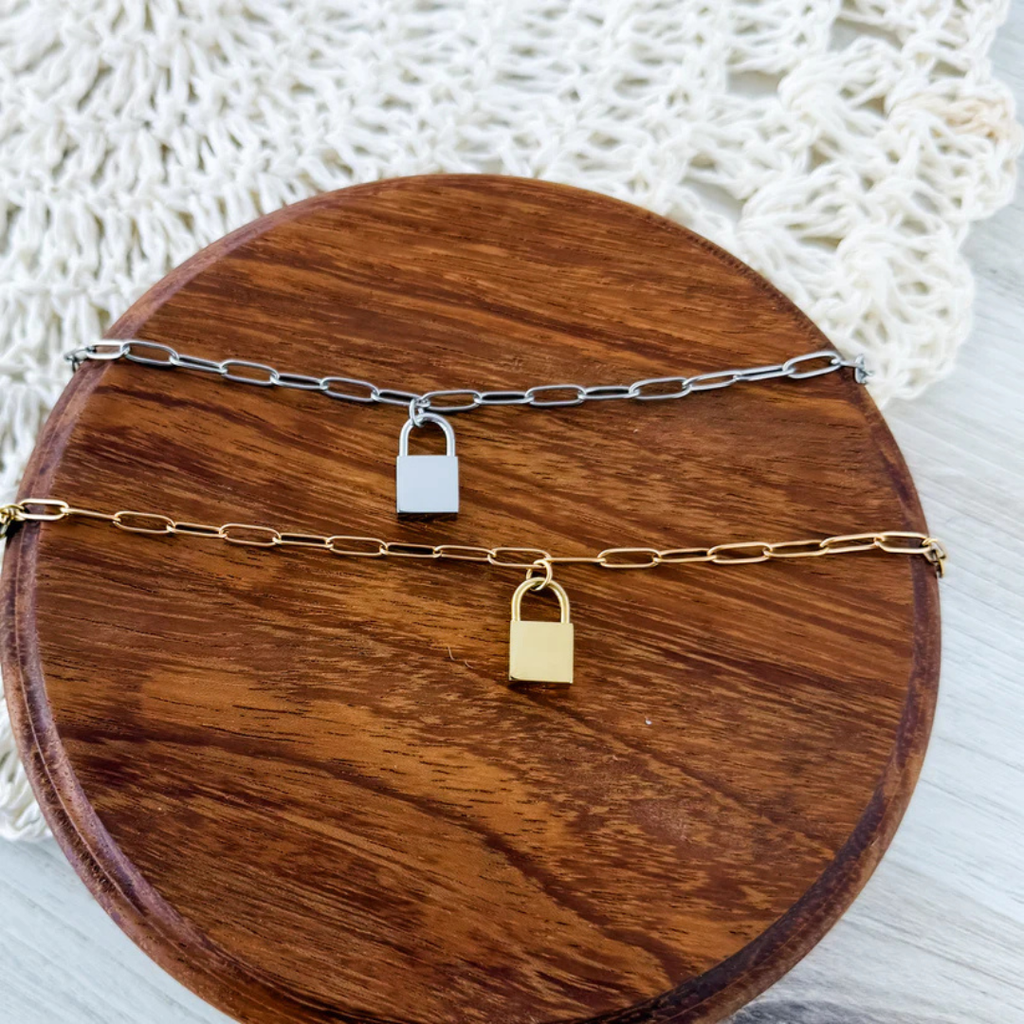 Matching silver and gold chain bracelets with lock pendants. 