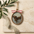 Decorative hanging ornament with a small dog inside, tied with a ribbon on a textured surface.