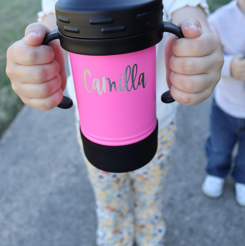 Child holding a sippy cup with their name engraved.