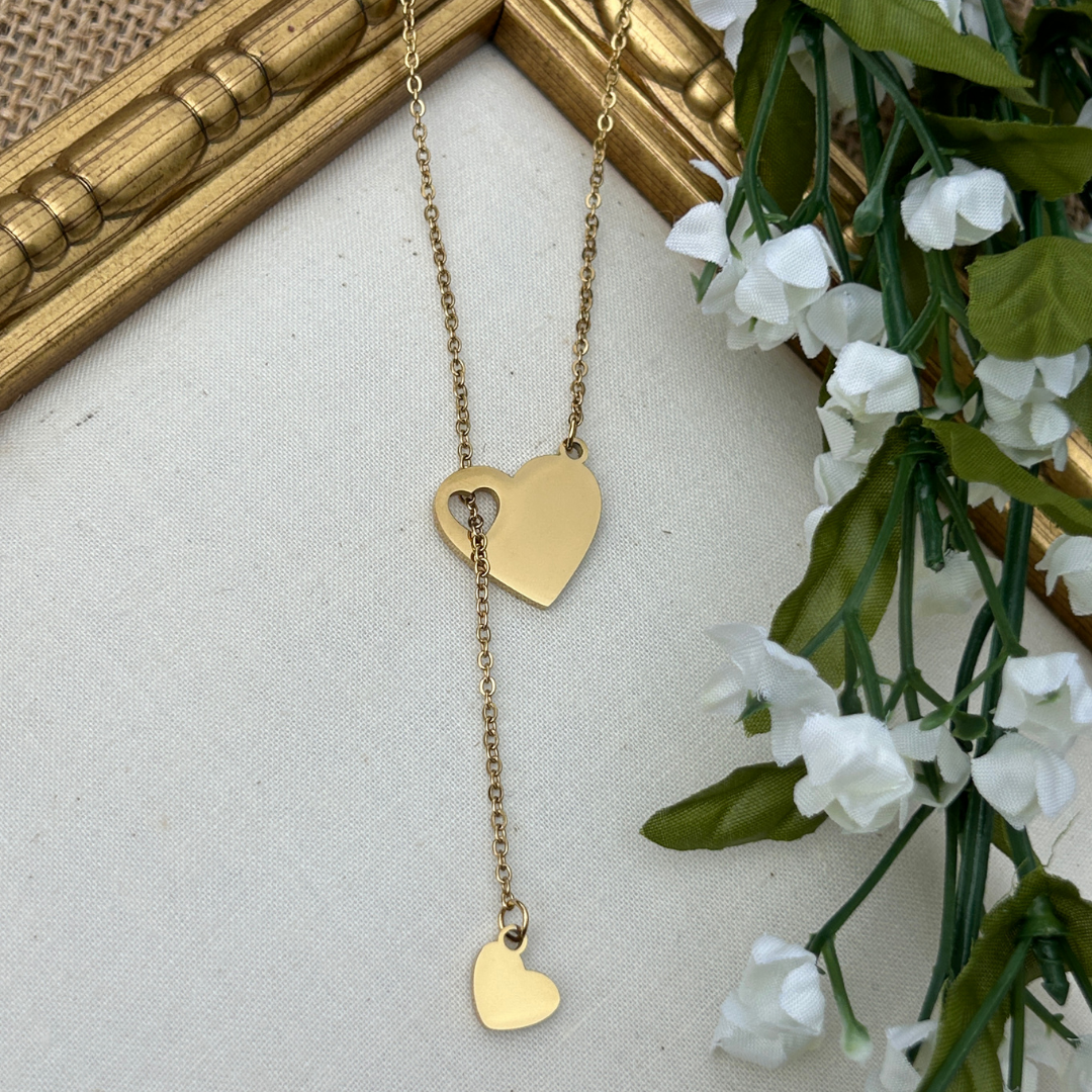 Gold heart-shaped necklace on a neutral background with decorative elements