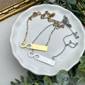 Three necklaces on a white dish with a gold frame and greenery in the background