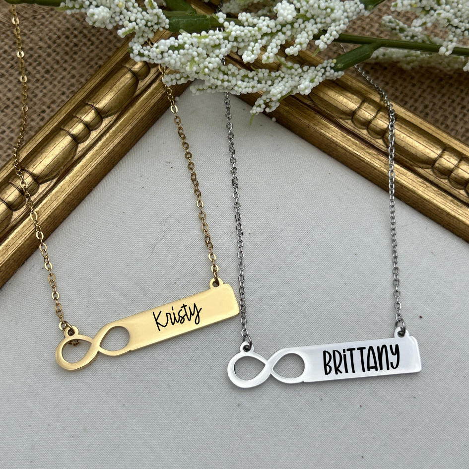 Two necklaces with engraved names on a neutral background